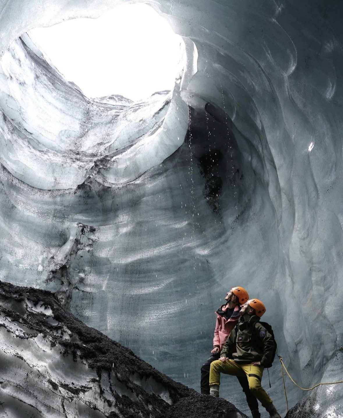 Guide touristique menant un petit groupe à travers les formations de glace noire et bleue à l'intérieur de la grotte de glace du Katla en Islande